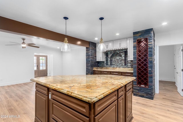 kitchen with pendant lighting, a center island, decorative backsplash, ceiling fan, and light wood-type flooring