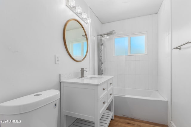 full bathroom with tiled shower / bath combo, vanity, toilet, and hardwood / wood-style flooring