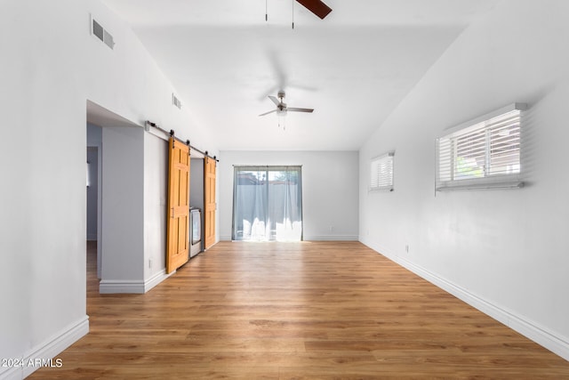 spare room featuring plenty of natural light, a barn door, ceiling fan, and wood-type flooring