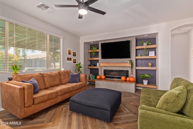 living room with ceiling fan, arched walkways, a glass covered fireplace, and visible vents