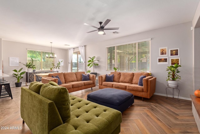 living area with ceiling fan with notable chandelier, visible vents, and baseboards