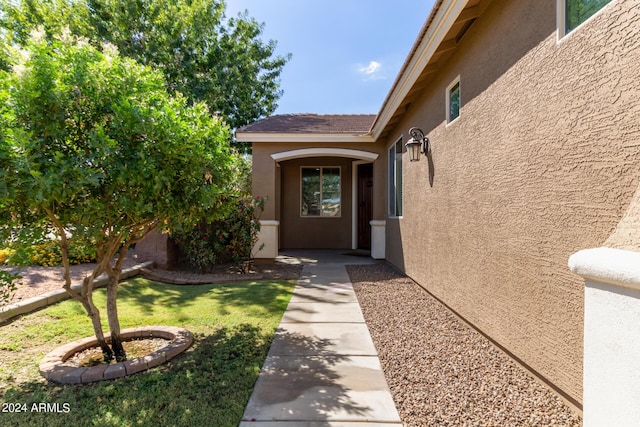 entrance to property with a yard and stucco siding