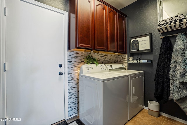 laundry area featuring light tile patterned flooring, washing machine and clothes dryer, and cabinets