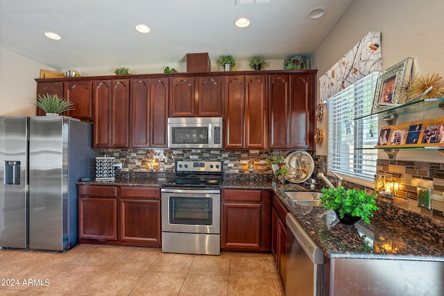 kitchen featuring light tile patterned flooring, sink, appliances with stainless steel finishes, dark stone countertops, and decorative backsplash