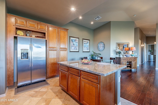 16336 E Ridgeline Dr, Fountain Hills, AZ 85268 - kitchen with light stone counters, brown cabinetry, stainless steel fridge with ice dispenser, visible vents, and a kitchen island