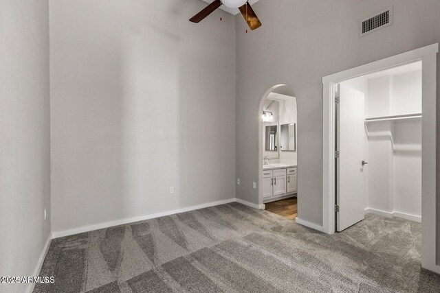 4343 E Soliere Ave Unit 2070, Flagstaff, AZ 86004 - unfurnished bedroom featuring light carpet, a spacious closet, ensuite bath, visible vents, and arched walkways