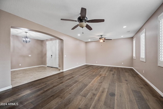 unfurnished room with ceiling fan with notable chandelier and light hardwood / wood-style flooring