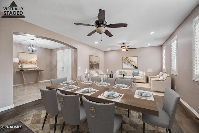 dining space with ceiling fan with notable chandelier and dark hardwood / wood-style flooring