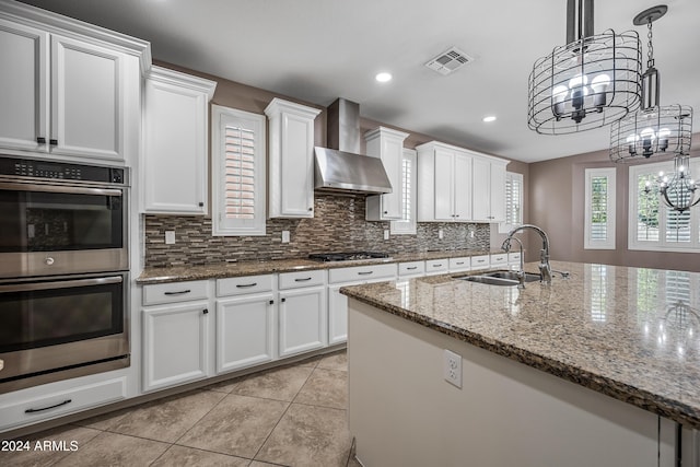 kitchen with wall chimney exhaust hood, white cabinetry, sink, and appliances with stainless steel finishes