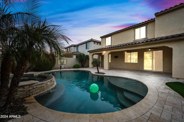 pool at dusk with a patio area, an in ground hot tub, and ceiling fan