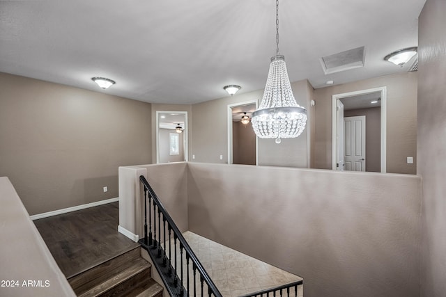 staircase with hardwood / wood-style floors and a notable chandelier