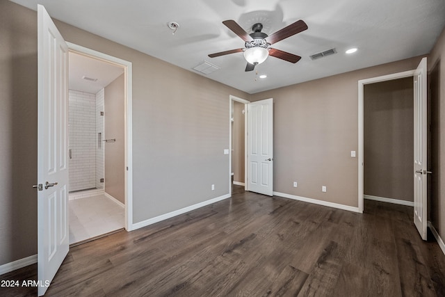 unfurnished bedroom with ensuite bathroom, ceiling fan, and dark wood-type flooring