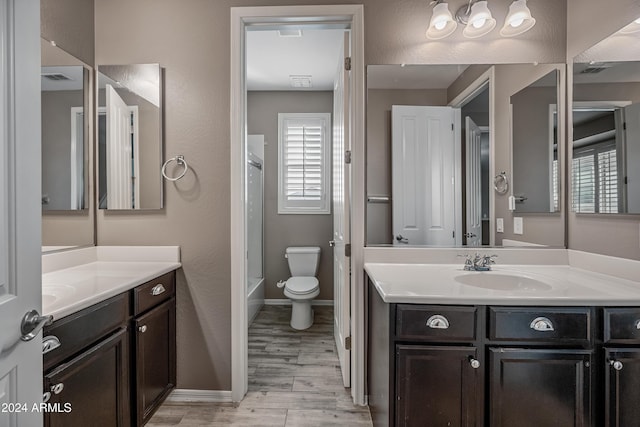 full bathroom with hardwood / wood-style floors, vanity,  shower combination, and toilet