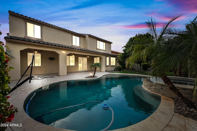 pool at dusk featuring a patio area and ceiling fan