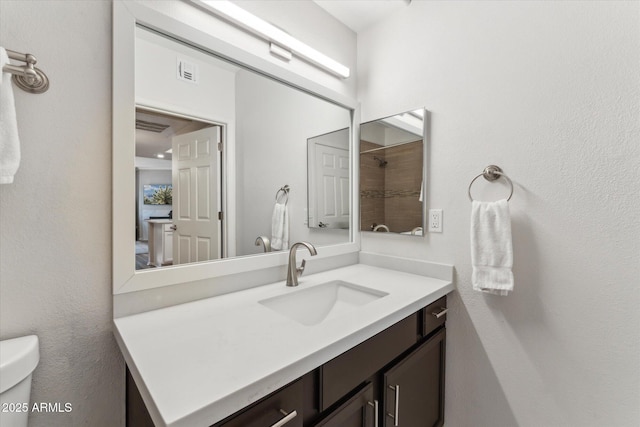 bathroom with toilet, visible vents, walk in shower, and vanity