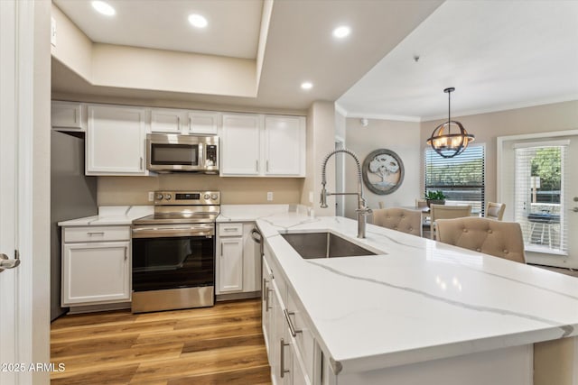 kitchen featuring light wood-style flooring, appliances with stainless steel finishes, white cabinets, and a sink