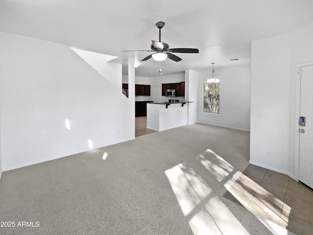 unfurnished living room featuring ceiling fan with notable chandelier and carpet