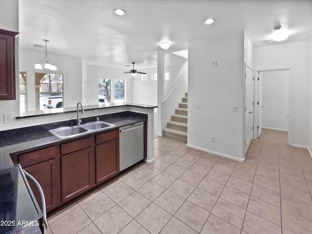 kitchen featuring dark countertops, a peninsula, stainless steel dishwasher, a sink, and light tile patterned flooring