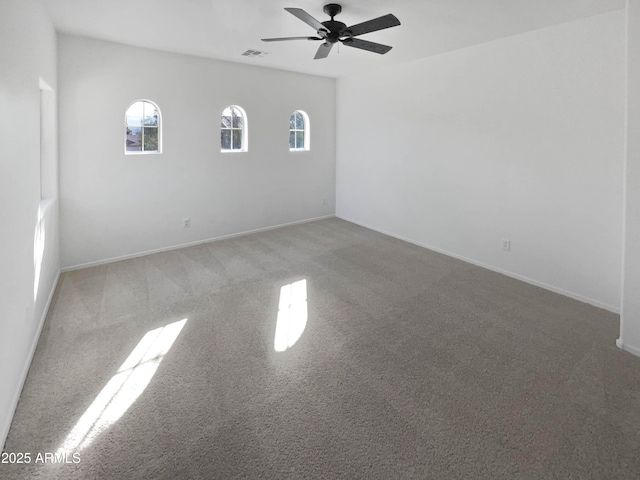 carpeted spare room with ceiling fan, visible vents, and baseboards