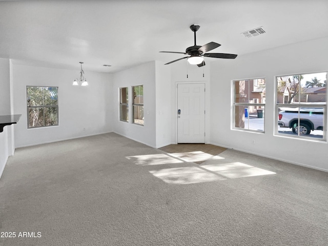 unfurnished living room with ceiling fan with notable chandelier, carpet flooring, visible vents, and baseboards