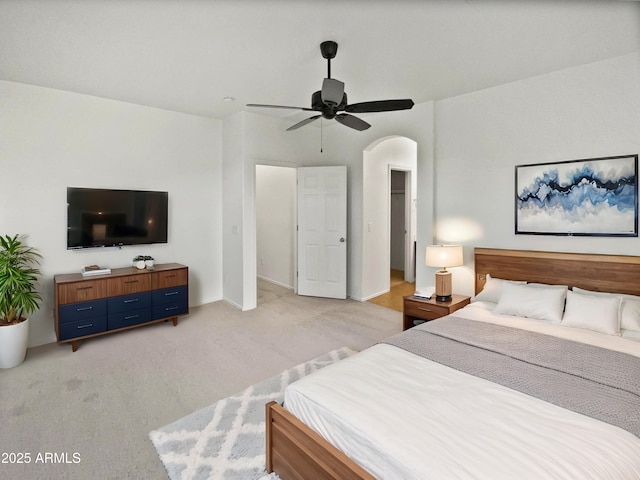 bedroom with arched walkways, light carpet, ceiling fan, and baseboards