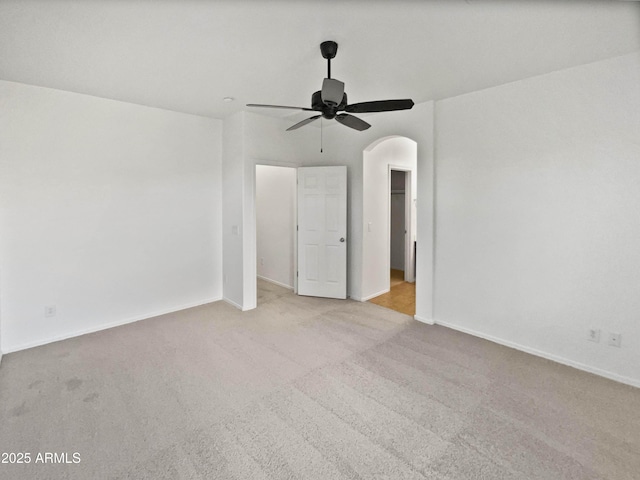 unfurnished bedroom featuring arched walkways, carpet floors, and baseboards