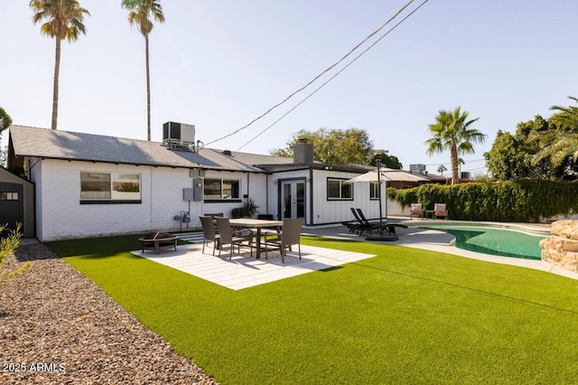 rear view of property featuring a fenced in pool, a fire pit, a patio area, and french doors