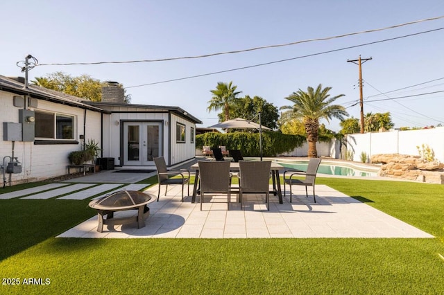 view of patio / terrace featuring a fenced in pool, a fire pit, and french doors