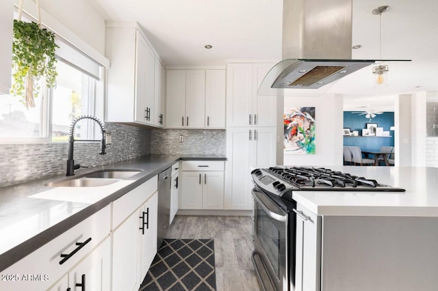 kitchen with sink, white cabinetry, hanging light fixtures, appliances with stainless steel finishes, and island exhaust hood