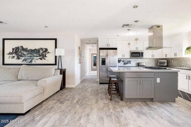 kitchen with white cabinetry, island range hood, hanging light fixtures, a kitchen island, and stainless steel appliances