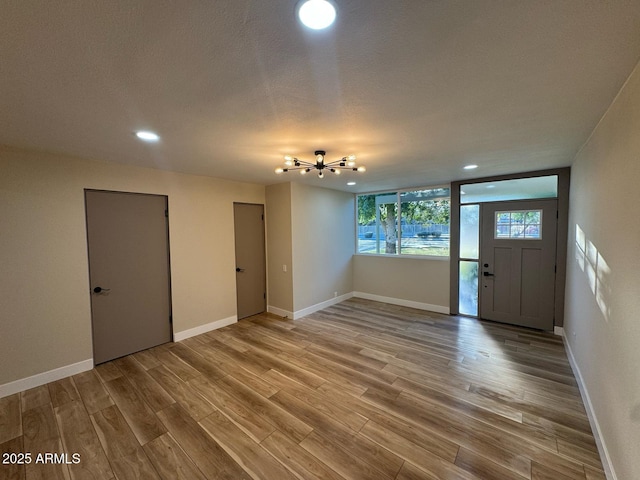 foyer featuring a textured ceiling, baseboards, wood finished floors, and recessed lighting