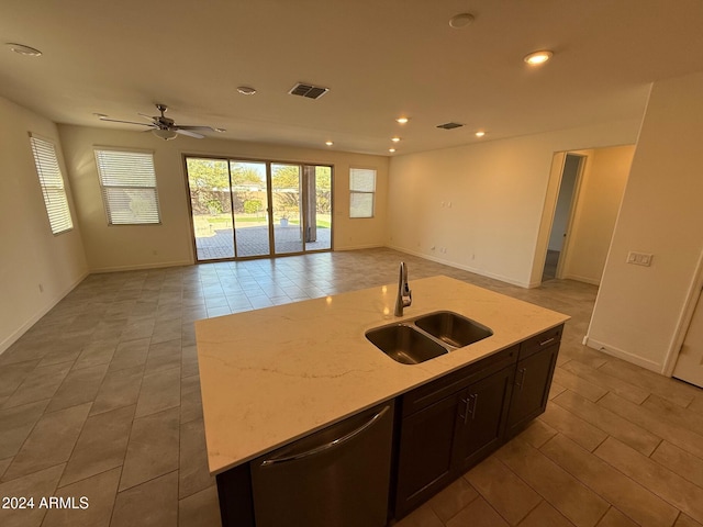 kitchen featuring light stone countertops, stainless steel dishwasher, ceiling fan, a kitchen island with sink, and sink