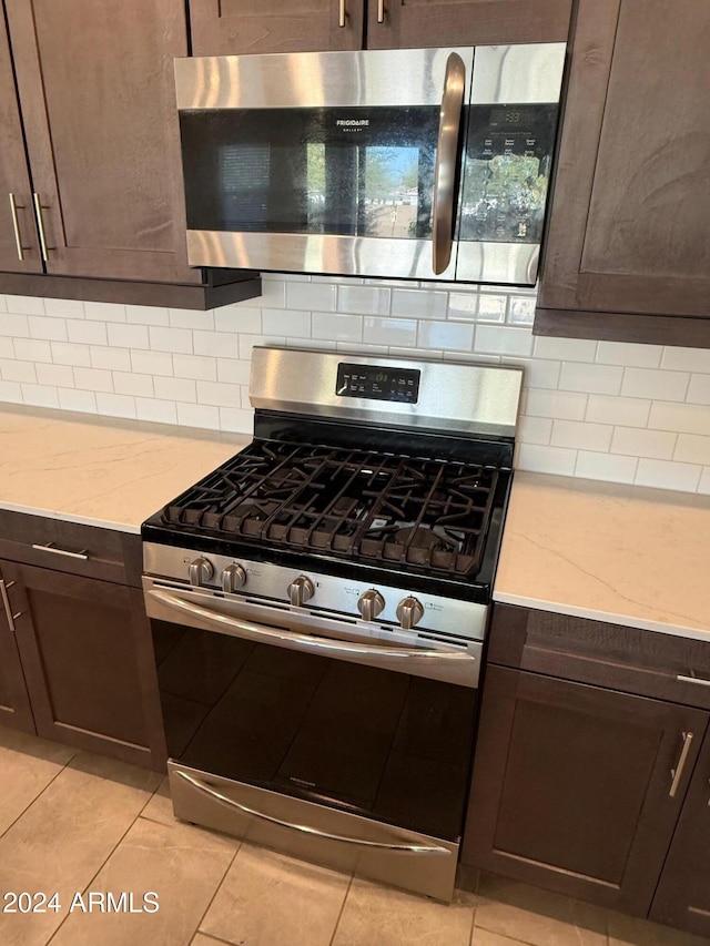 kitchen featuring tasteful backsplash, light stone counters, and stainless steel appliances