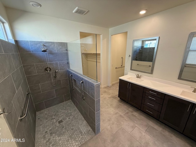 bathroom featuring tiled shower, vanity, and a healthy amount of sunlight