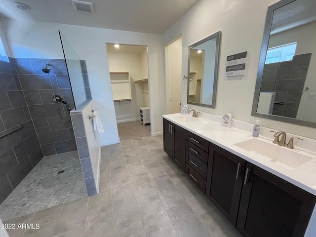 bathroom with tile patterned flooring, vanity, and tiled shower