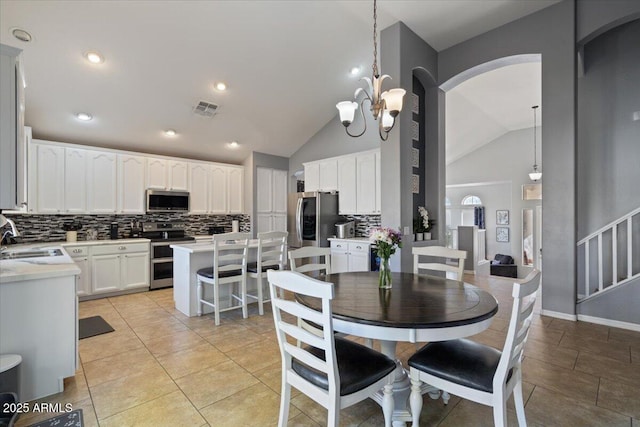 tiled dining area with sink, a chandelier, and vaulted ceiling