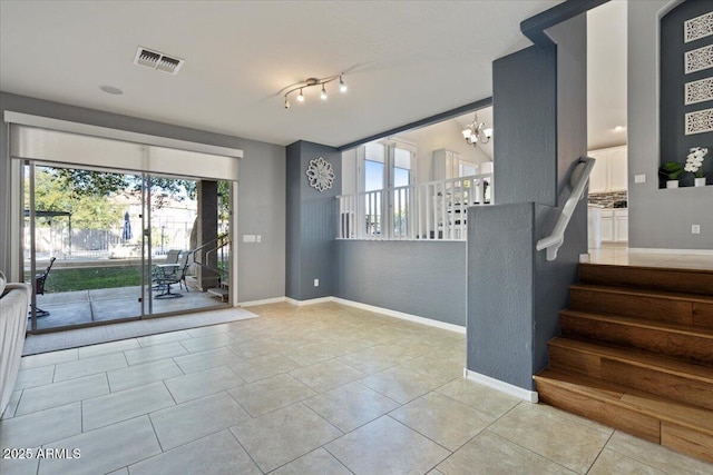 tiled spare room featuring a notable chandelier