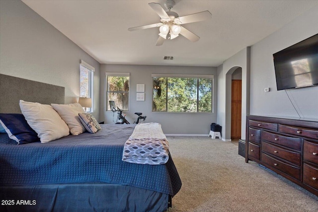 bedroom with multiple windows, ceiling fan, and light colored carpet