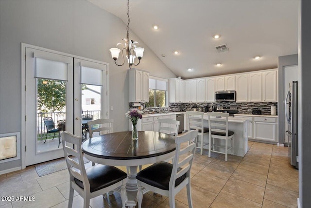 dining space featuring french doors, high vaulted ceiling, a chandelier, and light tile patterned floors