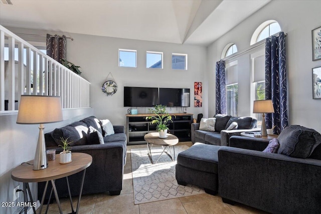 living room with a towering ceiling and light tile patterned floors