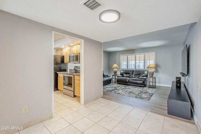 living room with light tile patterned floors, visible vents, and baseboards