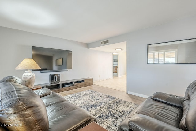 living room with wood finished floors, visible vents, and baseboards