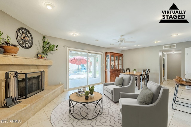 living area featuring ceiling fan, a fireplace, visible vents, and tile patterned floors