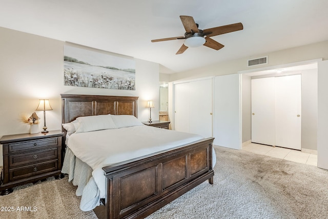 bedroom featuring a ceiling fan, visible vents, and light colored carpet