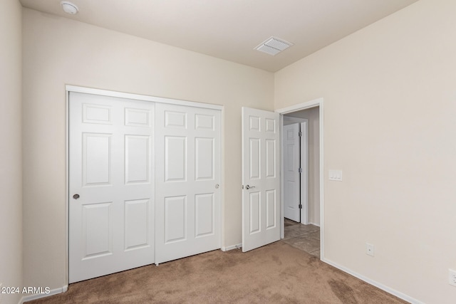 unfurnished bedroom featuring a closet and light colored carpet