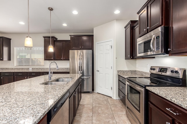 kitchen with hanging light fixtures, sink, light stone countertops, light tile patterned floors, and appliances with stainless steel finishes