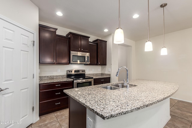 kitchen featuring appliances with stainless steel finishes, sink, dark brown cabinets, decorative light fixtures, and a center island with sink