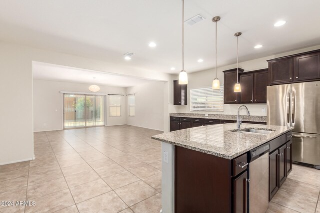 kitchen with sink, stainless steel appliances, dark brown cabinetry, pendant lighting, and a center island with sink