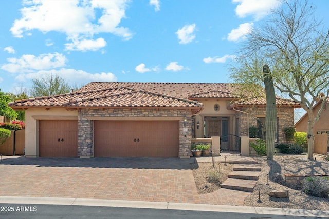 mediterranean / spanish-style house featuring decorative driveway, stone siding, and a tile roof