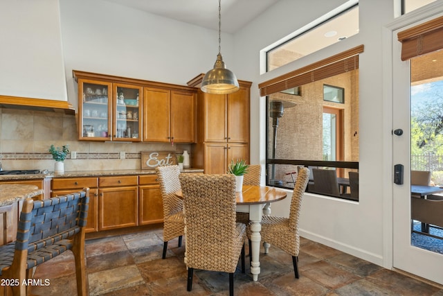 dining room featuring stone tile flooring, baseboards, and a high ceiling